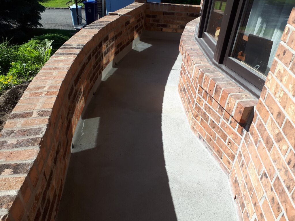 Rampe en maçonnerie en forme de S et crépi du balcon à Laval